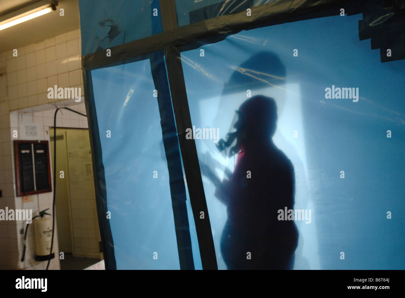 Man in full protective clothing inside a secured environment cleaning