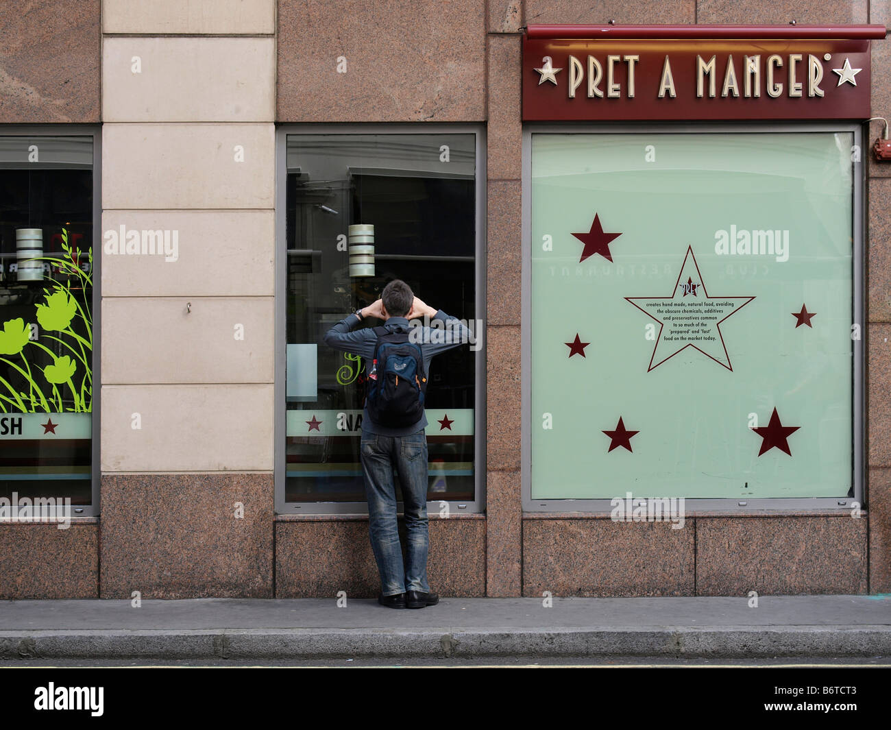 Man peeking through window of closed restaurant London UK Stock Photo