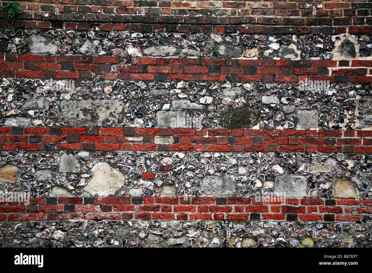 flint and stone wall with three course horizontal brick layers Stock