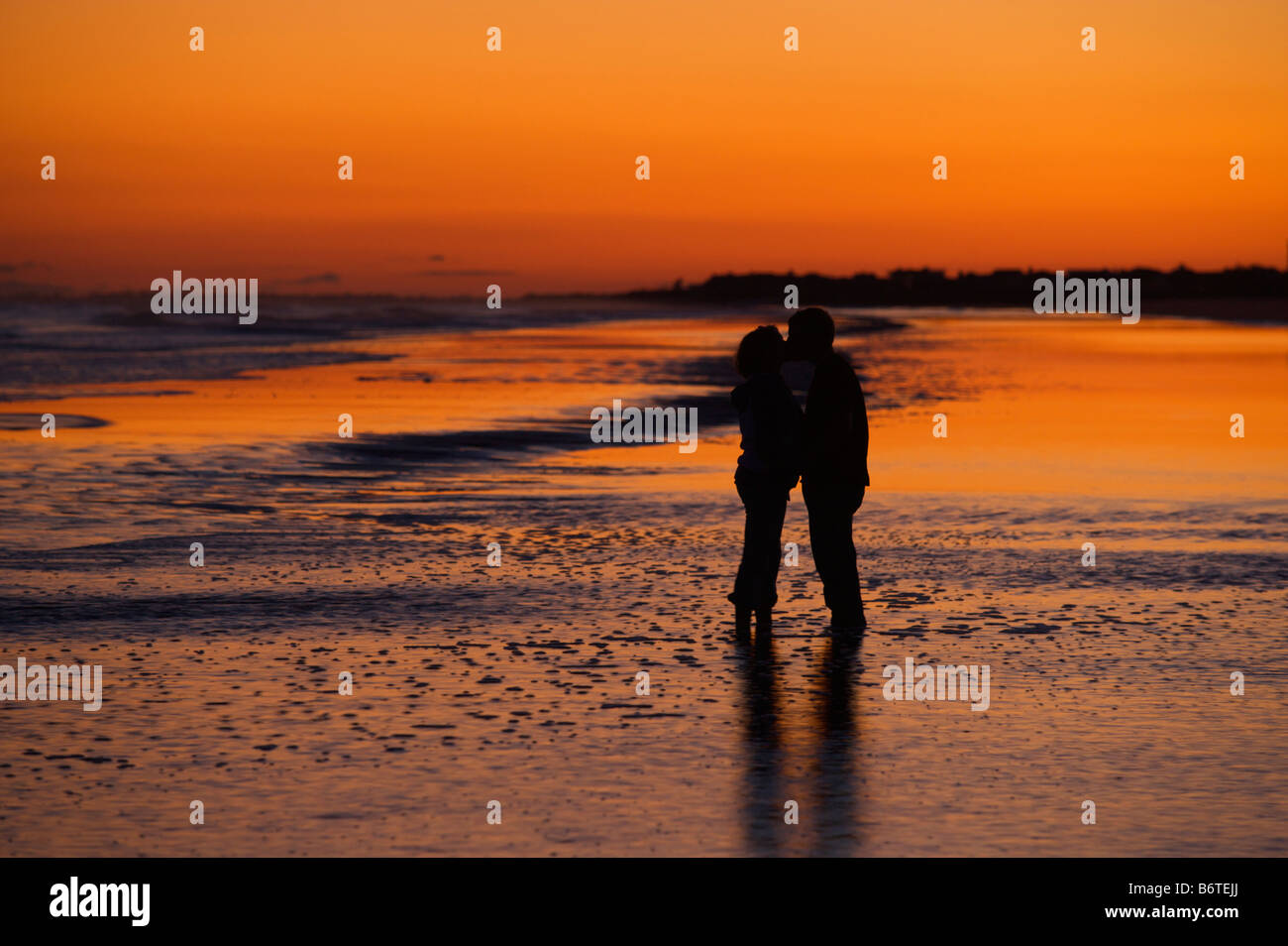 A couple embrace during sunset on the beach on Isle of Palms South Carolina Stock Photo