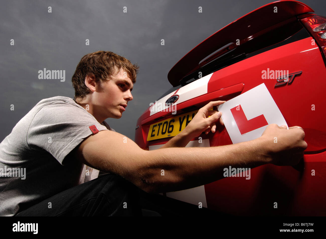 learner driver putting L plates on a ford fiesta ST Stock Photo