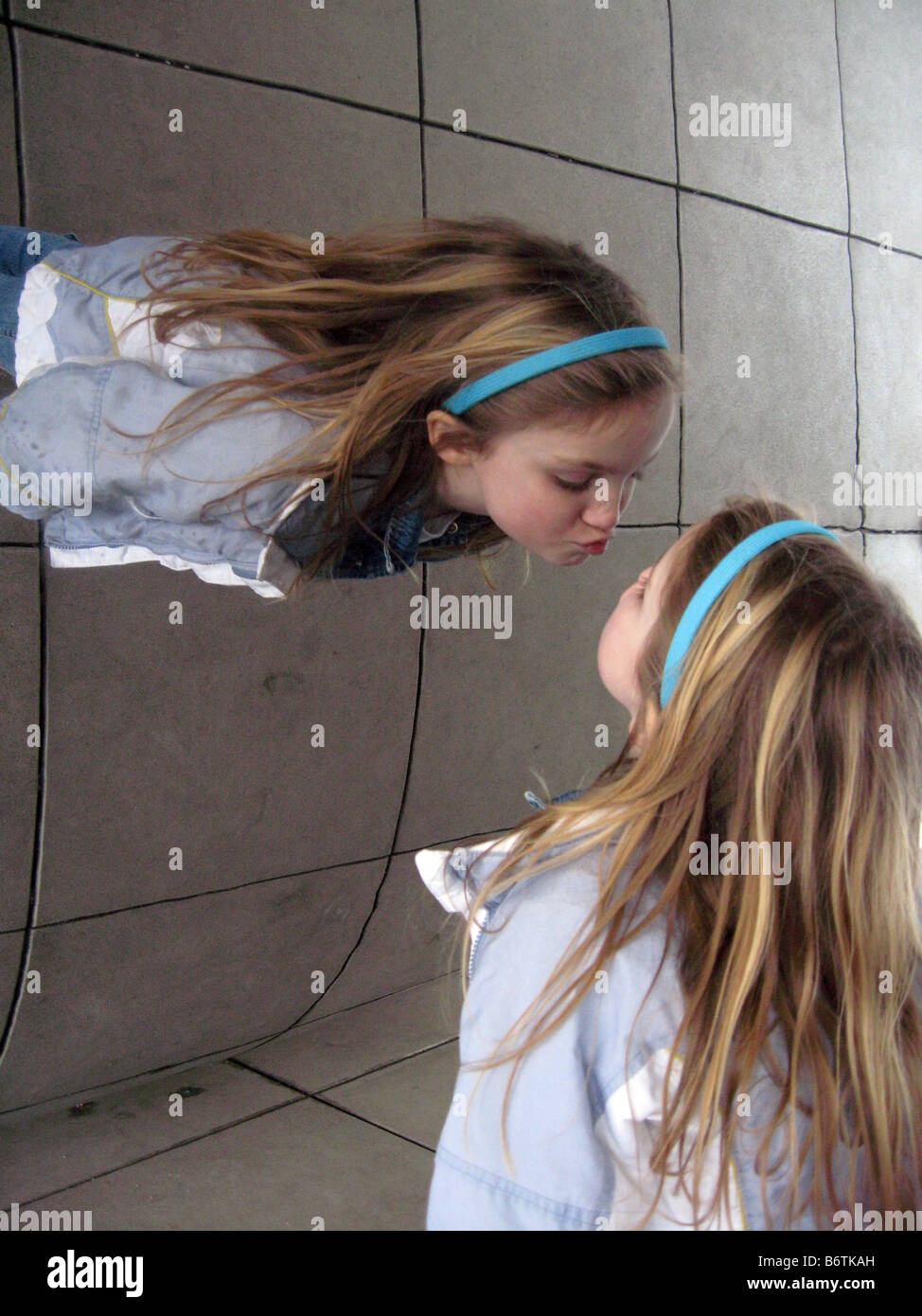 Young girl viewing herself from a unique perspective at the Millennium Park Bean sculpture in Chicago Stock Photo