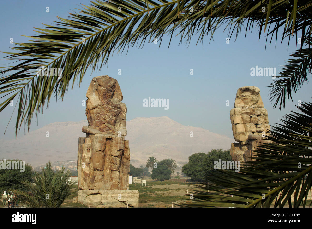 The Colossi of Memnon are two massive stone statues of Pharaoh Amenhotep III on the West Bank of the River Nile. Stock Photo