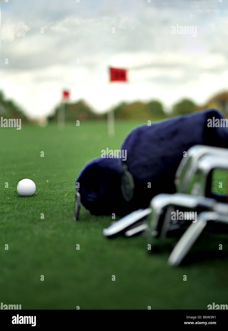 a singe golf ball placed on grass infront of a golf clubs Stock Photo