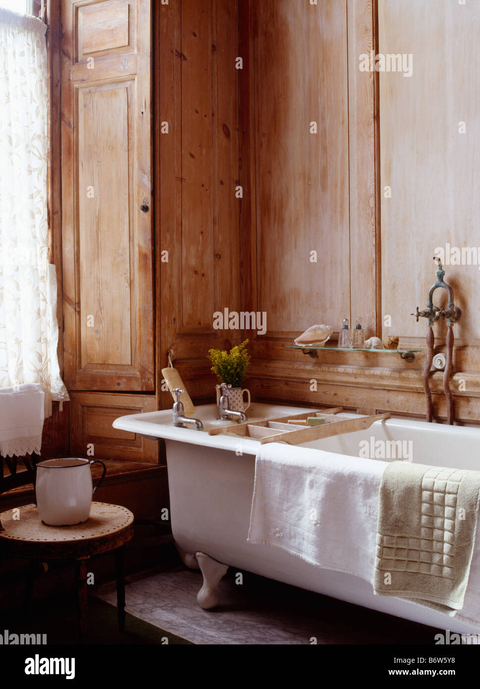White rolltop bath in panelled bathroom with wooden shutters Stock