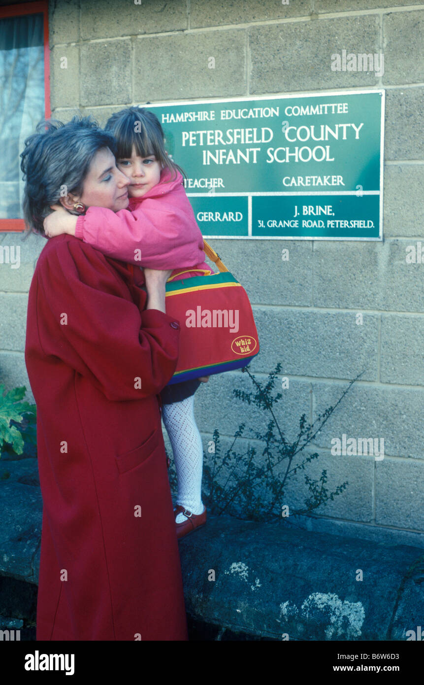 mother giving her daughter a hug outside infant school on her first day at school Stock Photo