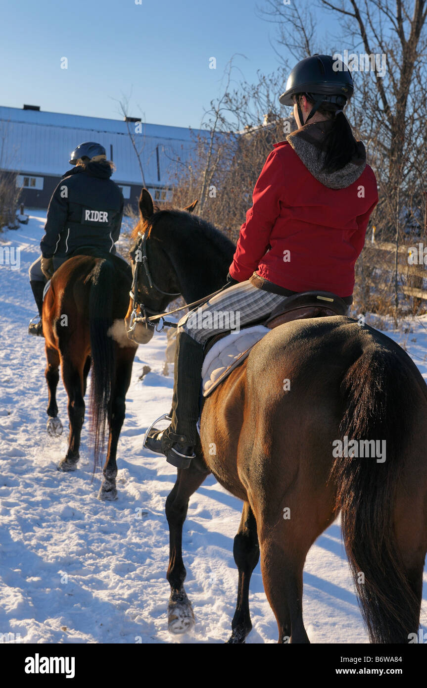 Two Female teenagers on horseback walking back to the barn after a winter hack Stock Photo