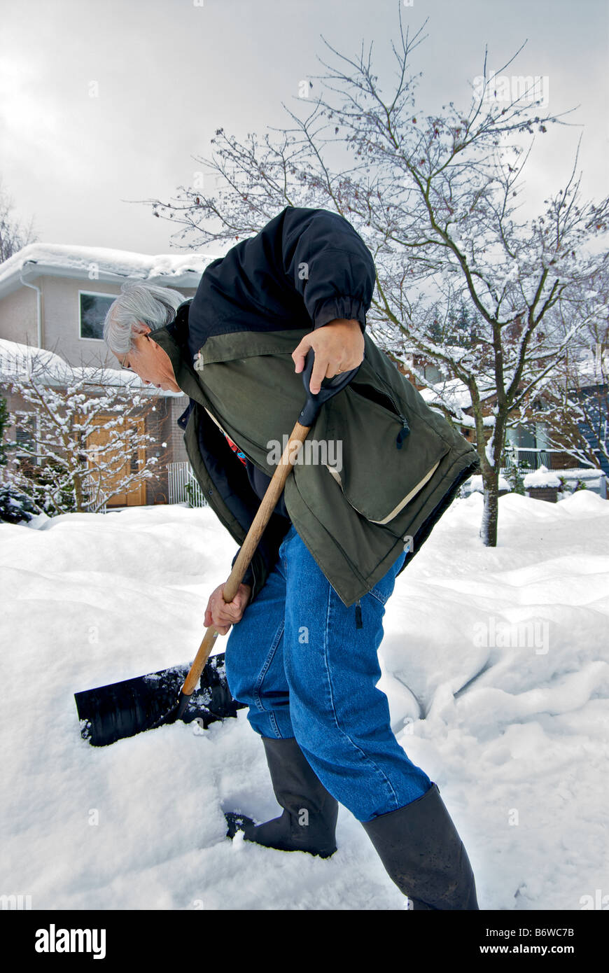 Man using proper bent knee stance for shoveling snow after a big snowstorm Stock Photo