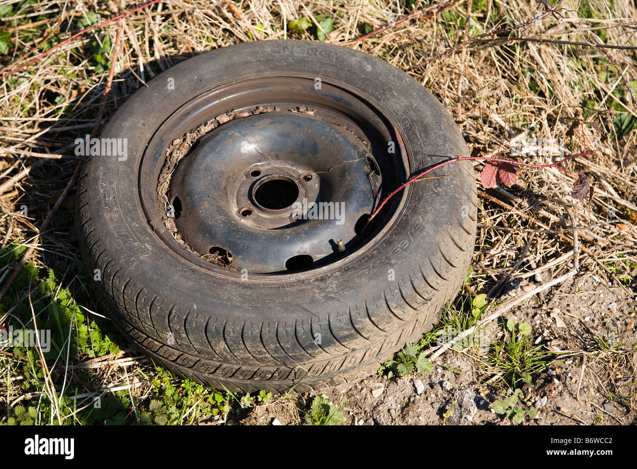 An old abandoned car wheel and tyre dumped by the side of the road ...