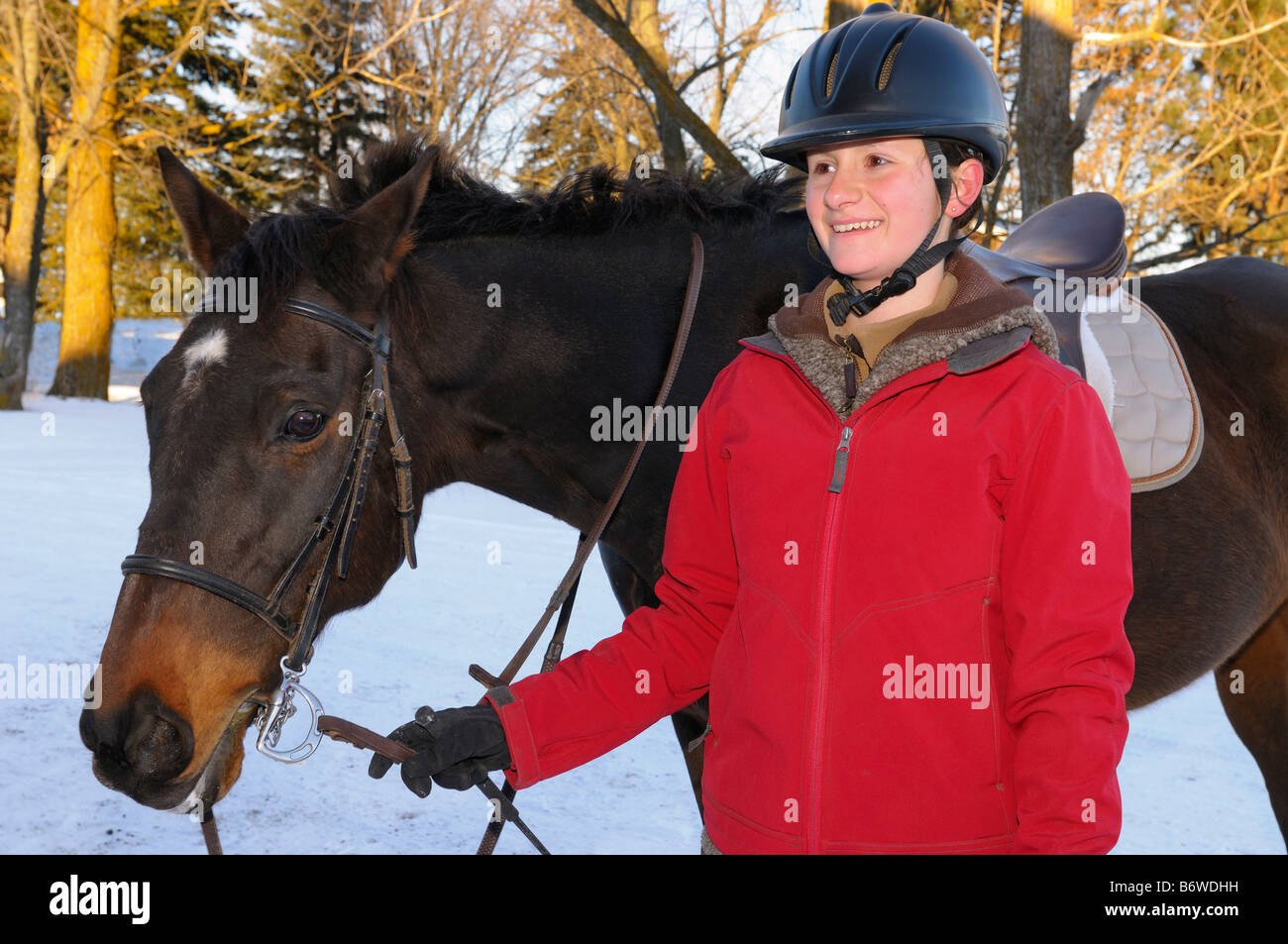 Relaxed happy teenage rider walking her horse back to the barn after a winter hack Stock Photo