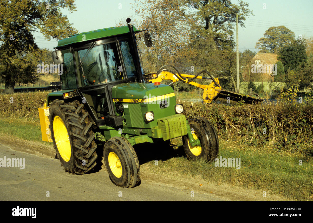 Farmer flailing hawthorn hedge / John Deere 2140 Tractor, Wiltshire, UK.
