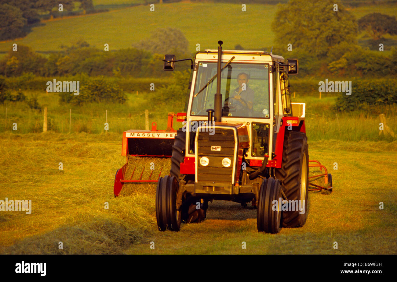 Farmer with old Massey Ferguson 690 Tractor and 124 Hay Baler, Wiltshire, UK.