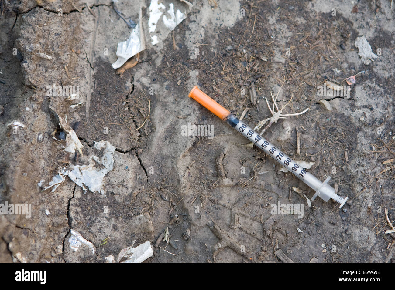 A hypodermic needle left laying on the ground in an inner city slum. Stock Photo