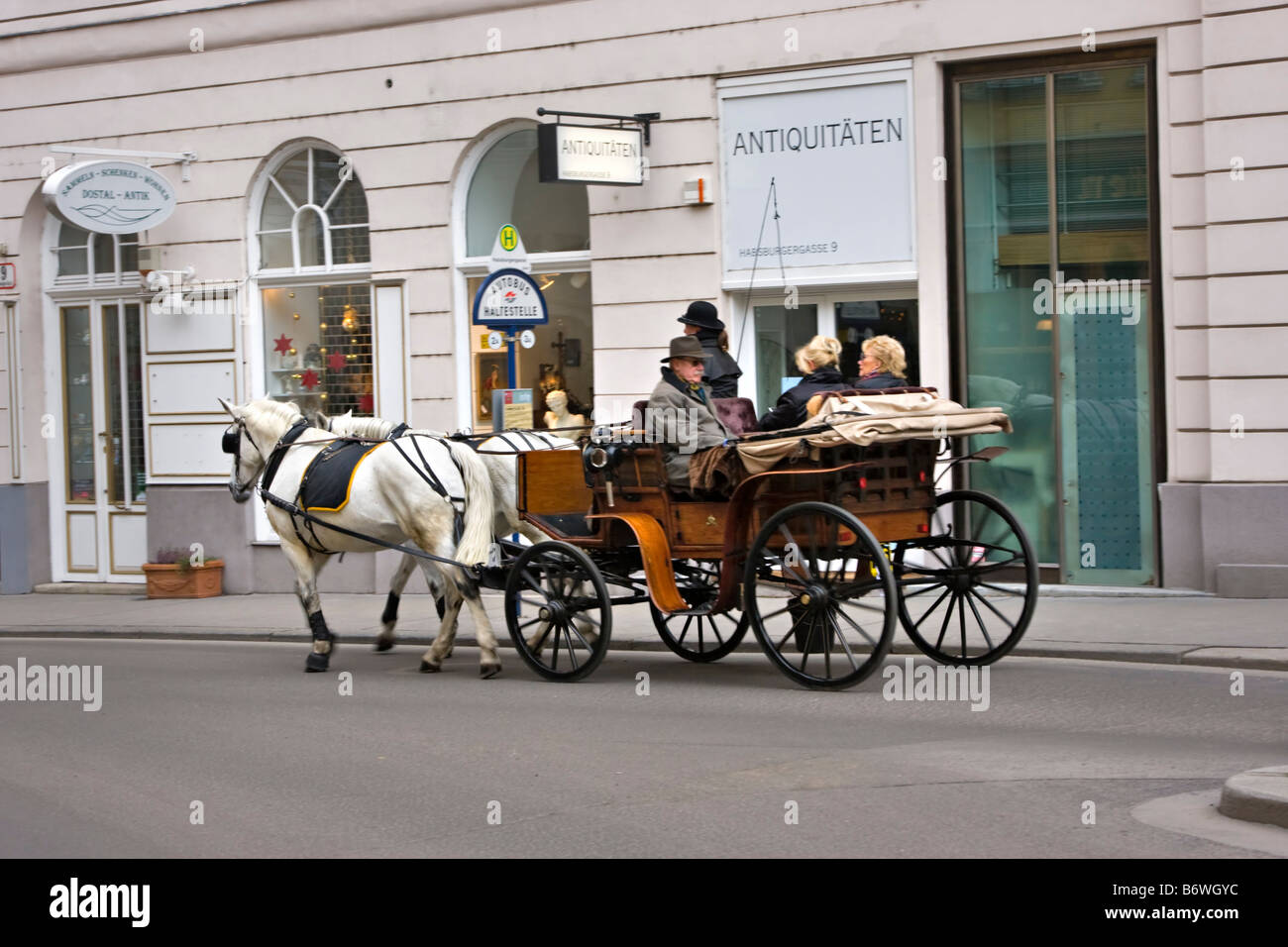 Fiaker in Vienna driving tourists past an antique shop Stock Photo