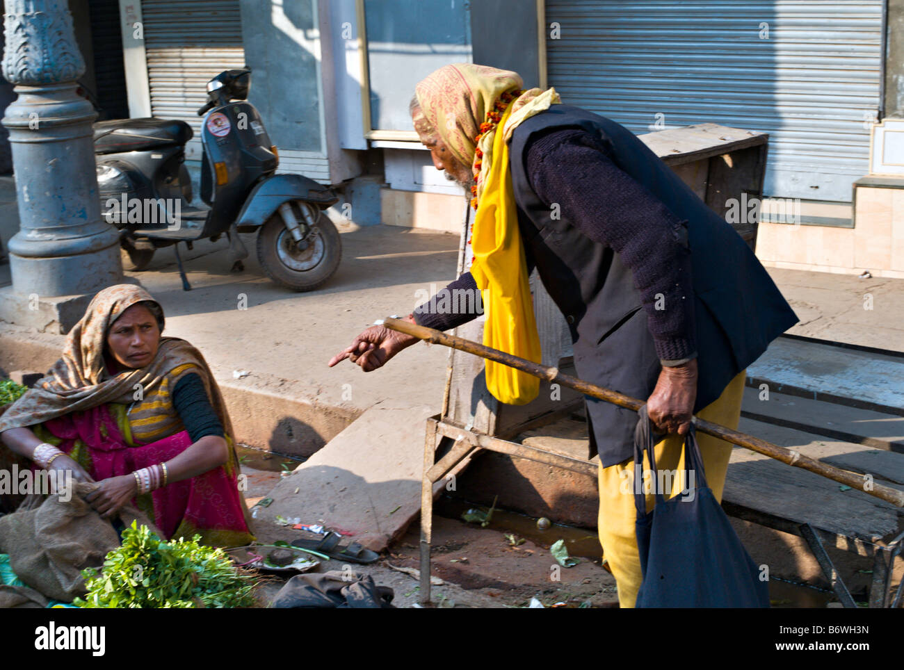 INDIA VARANASI Indian woman in colorful saris selling beautiful vegetables on the street in Varanasi as an elderly Sadu Stock Photo