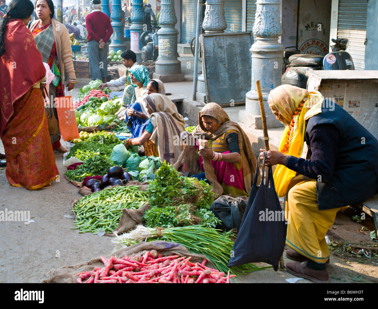 INDIA VARANASI Indian women in colorful saris selling beautiful vegetables on the street in Varanasi with an elderly Sadu Stock Photo