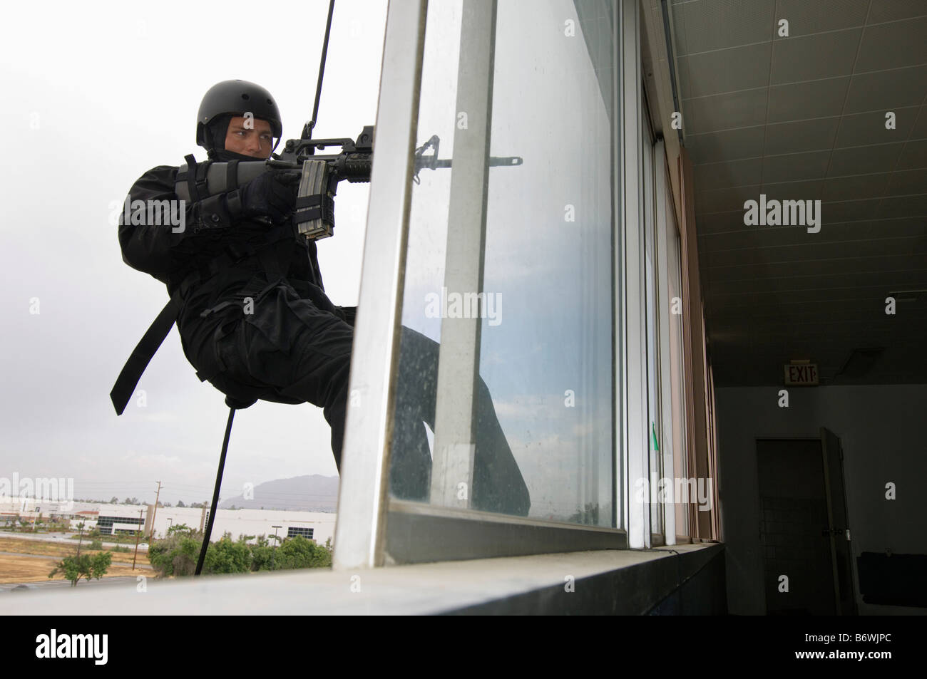 SWAT Team Officer Rappelling and Aiming Gun Stock Photo
