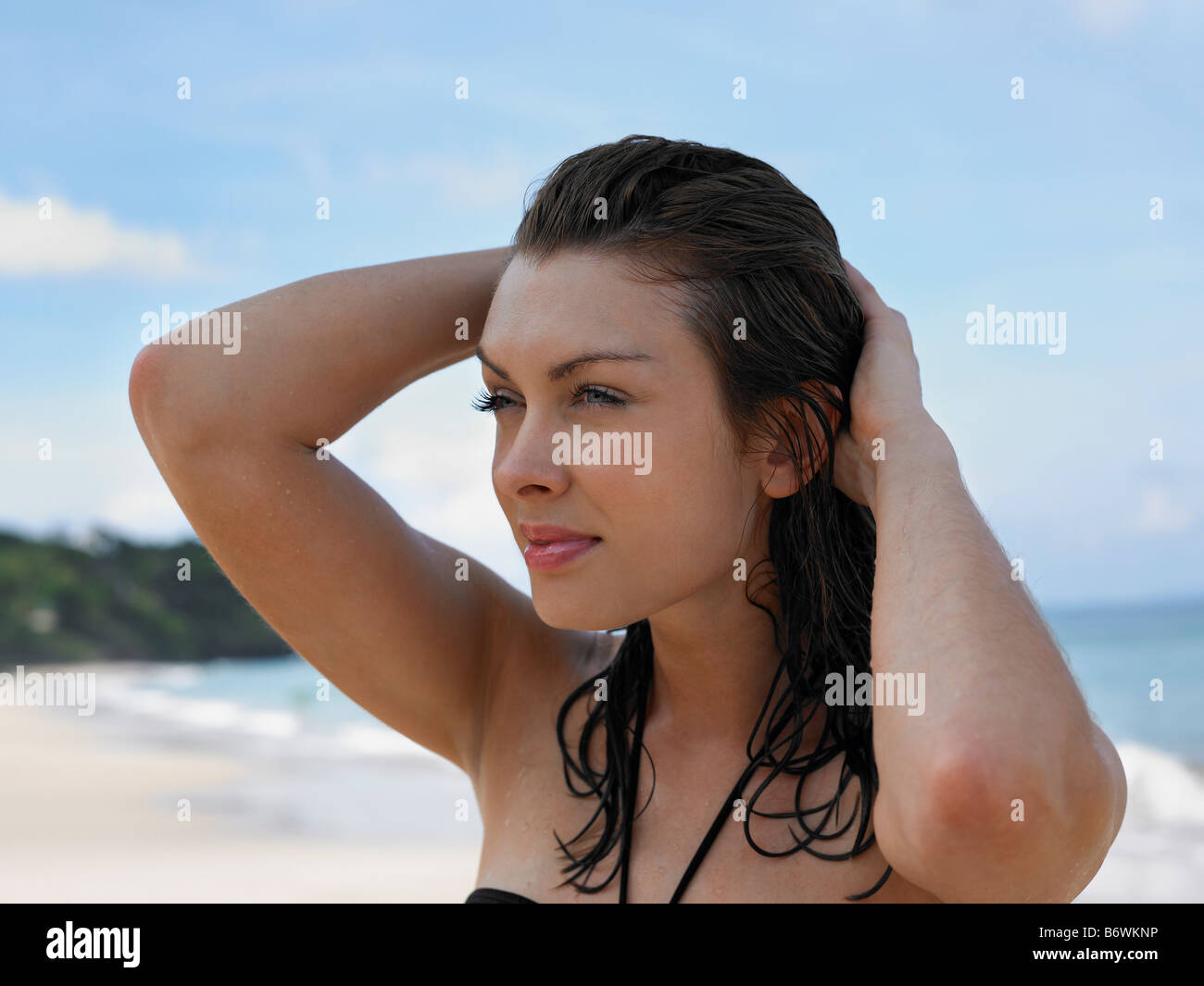 Young Woman at Beach with Hands in Hair Stock Photo