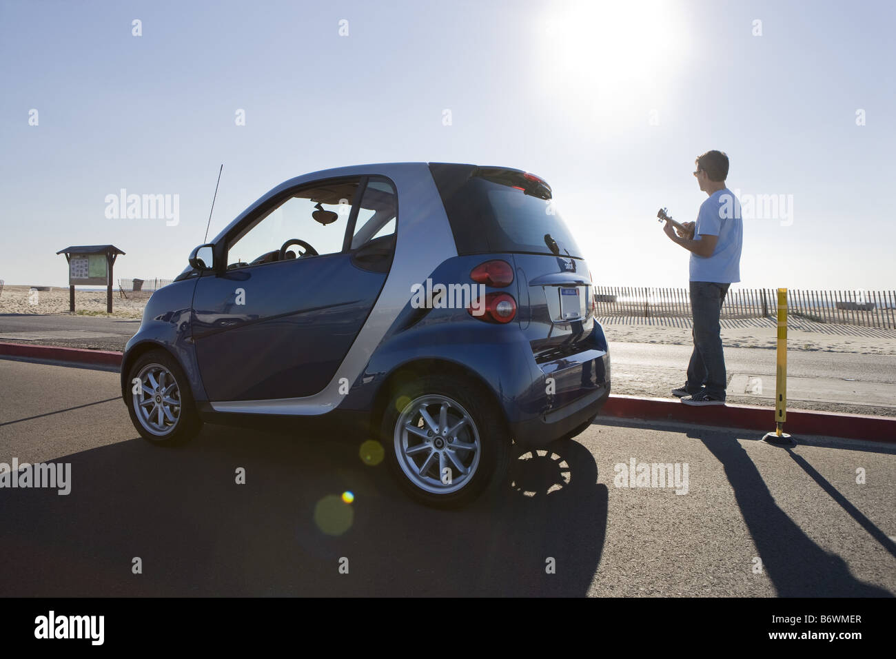 Young man standing by Smartcar at beach Stock Photo
