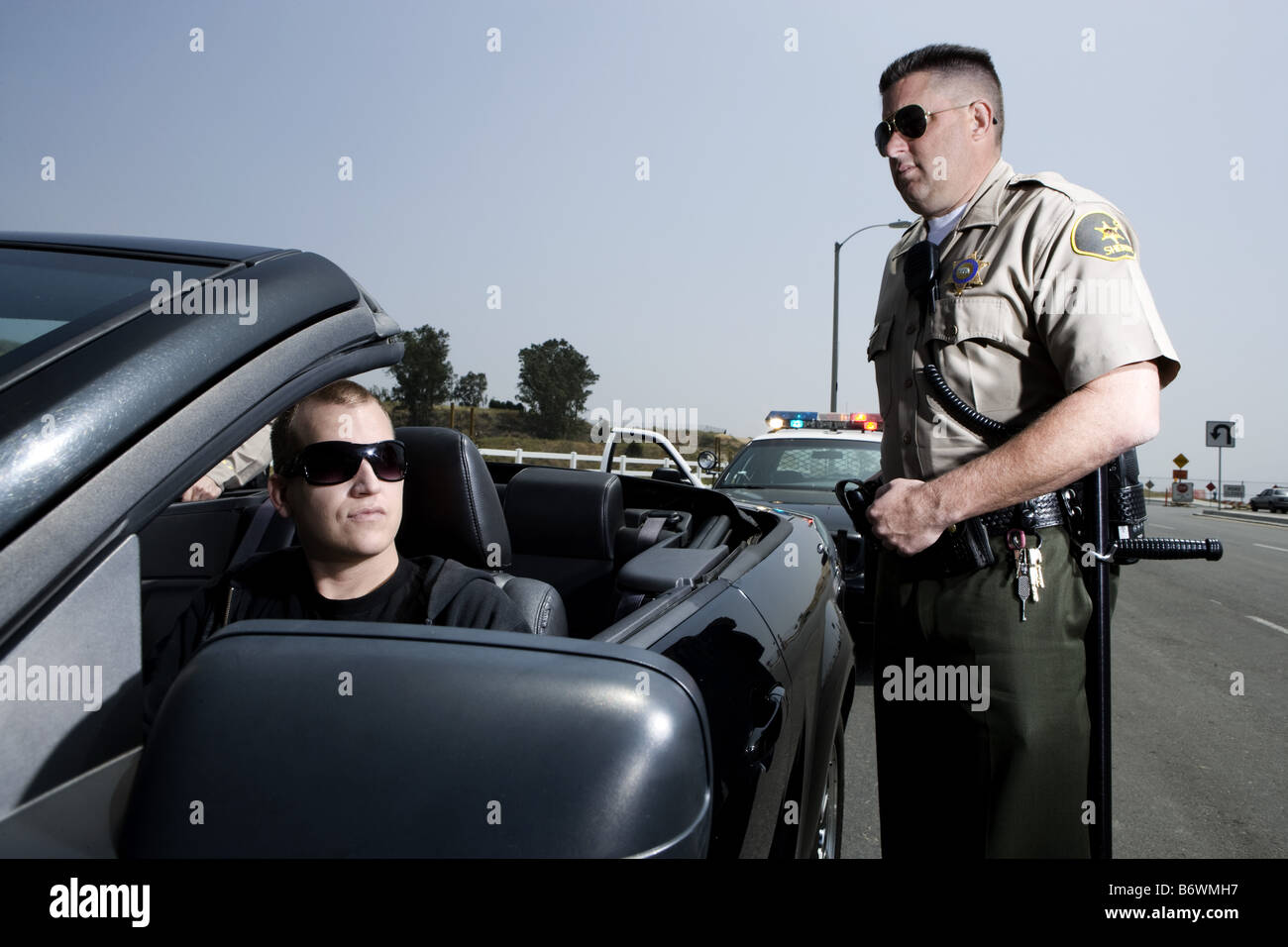 Police officer standing by man in Mustang Stock Photo