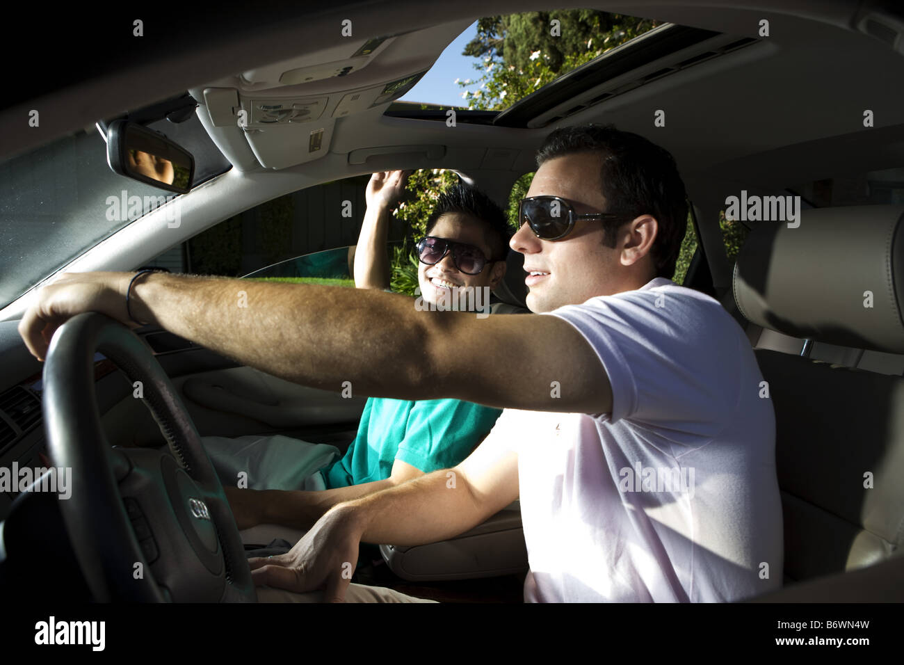 Two men in car smiling as they drive to golf Stock Photo - Alamy