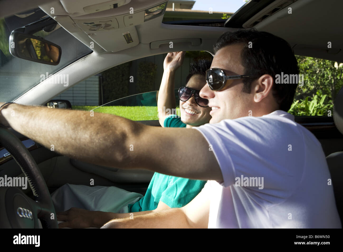 Two men in car smiling as they drive to golf Stock Photo - Alamy