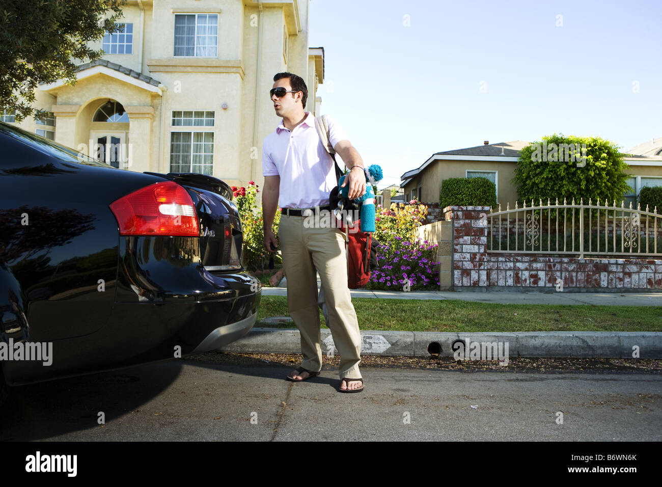 Golfer puts clubs into car trunk outside home Stock Photo Alamy