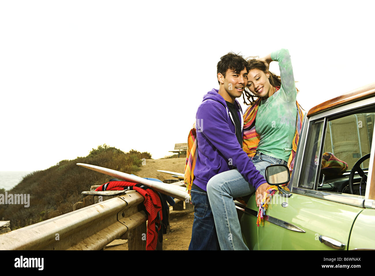 couple embrace on hoof of vintage car at beach Stock Photo