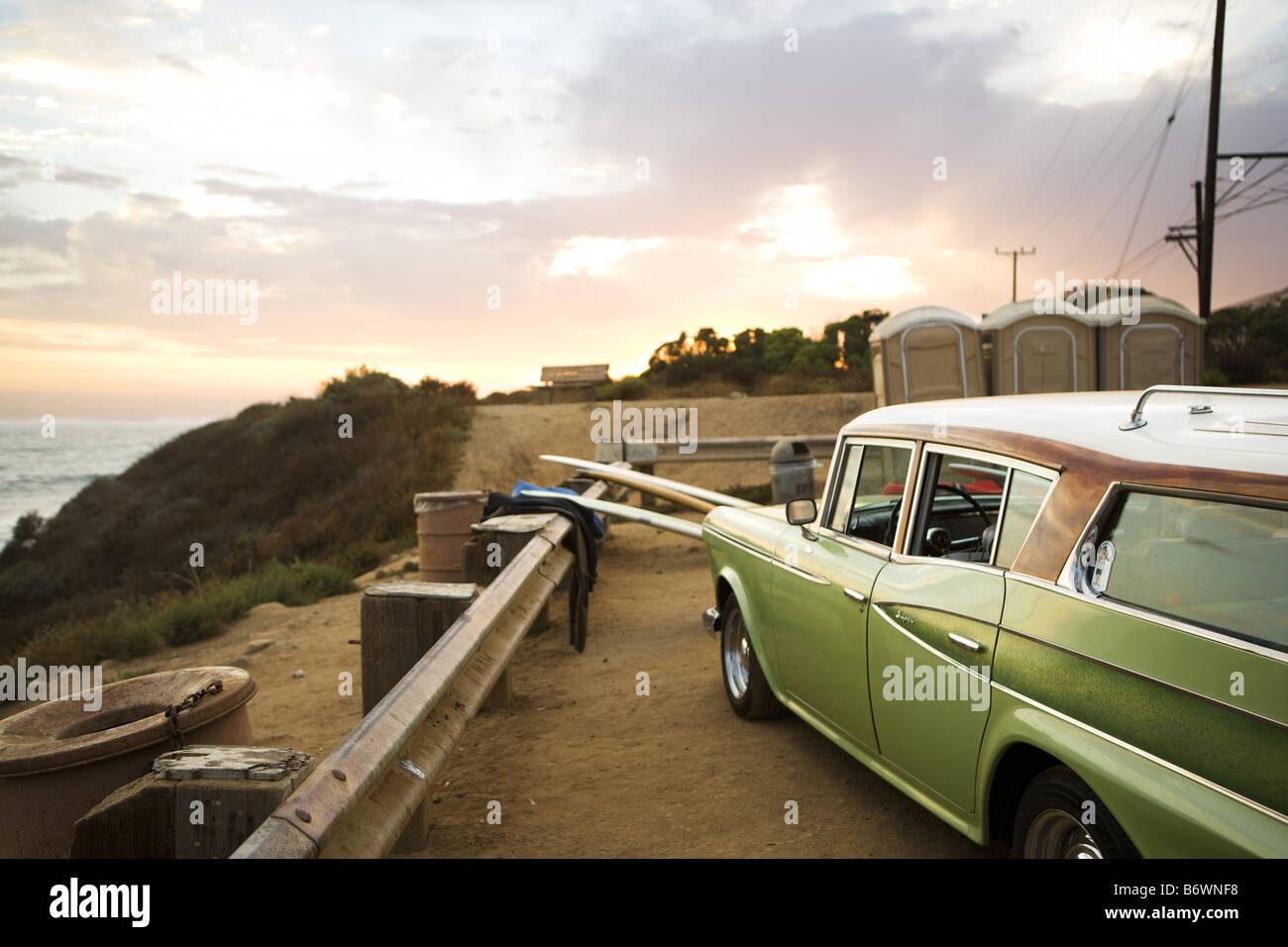 surfboards sit next to vintage car at beach Stock Photo