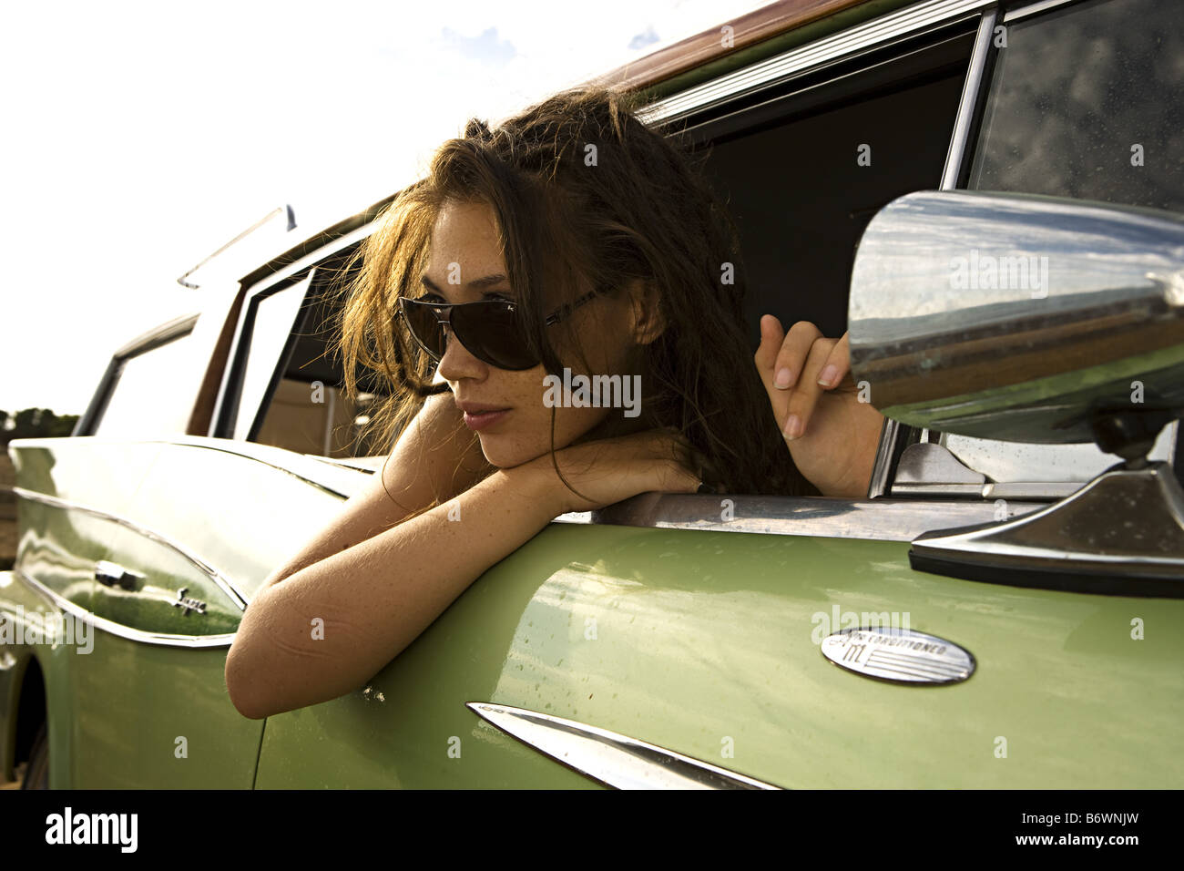 girl leans out of window in vintage car at beach Stock Photo