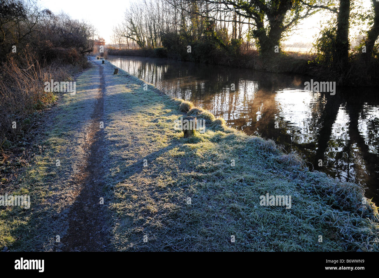 A footpath runs alongside the River Wey Navigation in Surrey England on a cold and frosty winter morning. Stock Photo