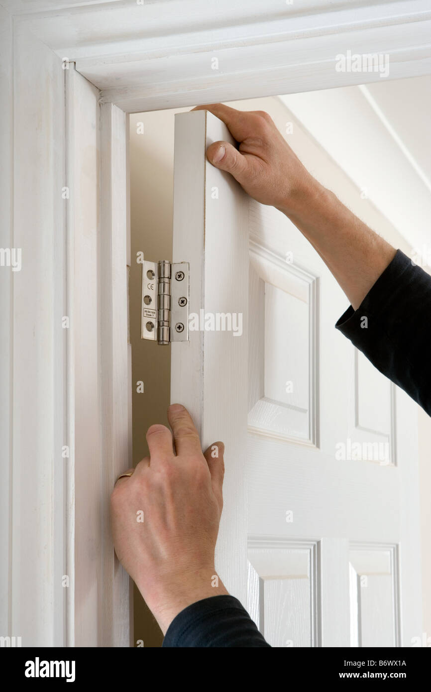 A builder fixing a door to a hinge Stock Photo Alamy