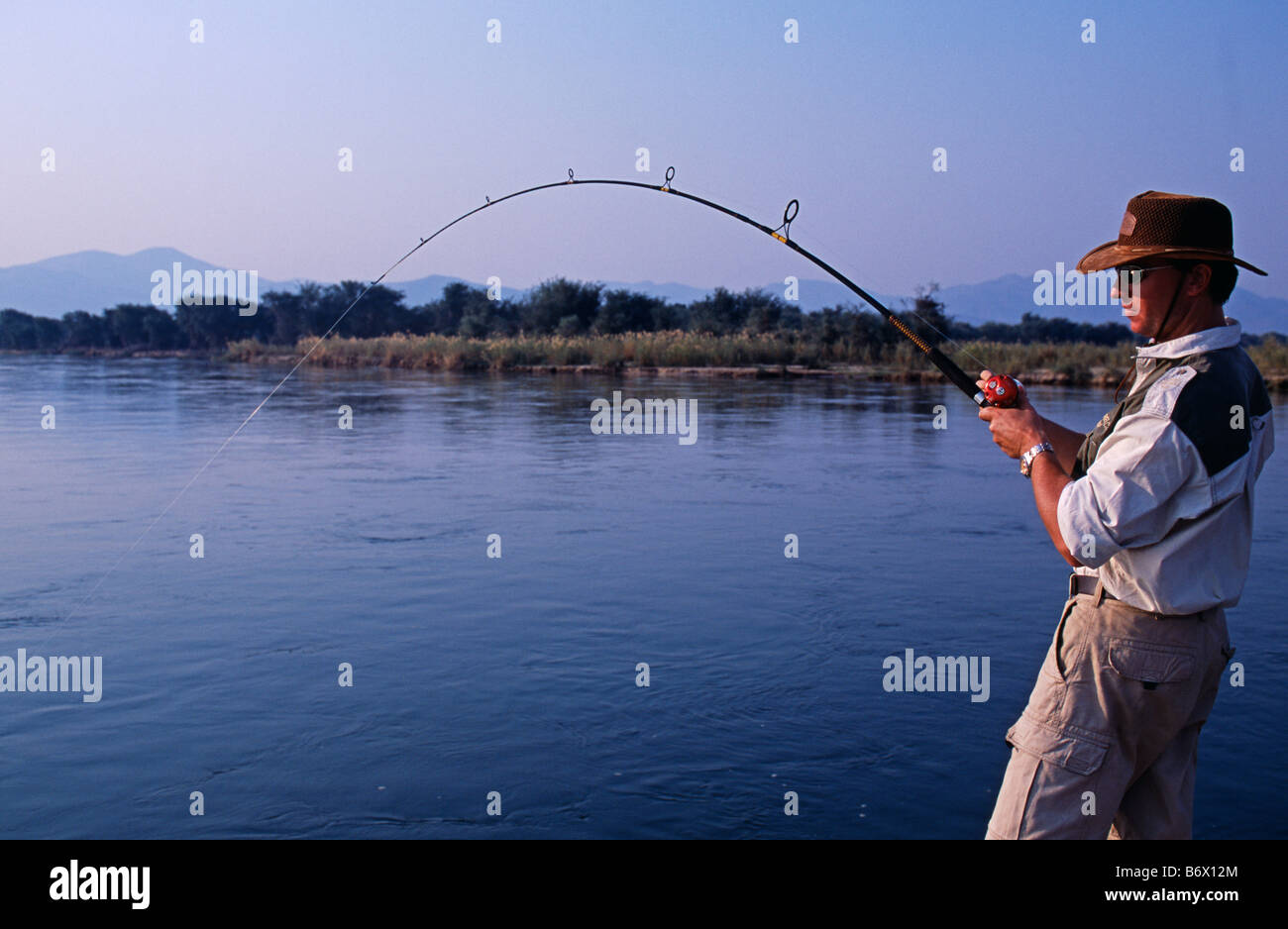 Zambia, Lower Zambezi National Park. Reeling in a tiger fish (the world s finest fighting freswater fish) on the Zambezi river. Stock Photo