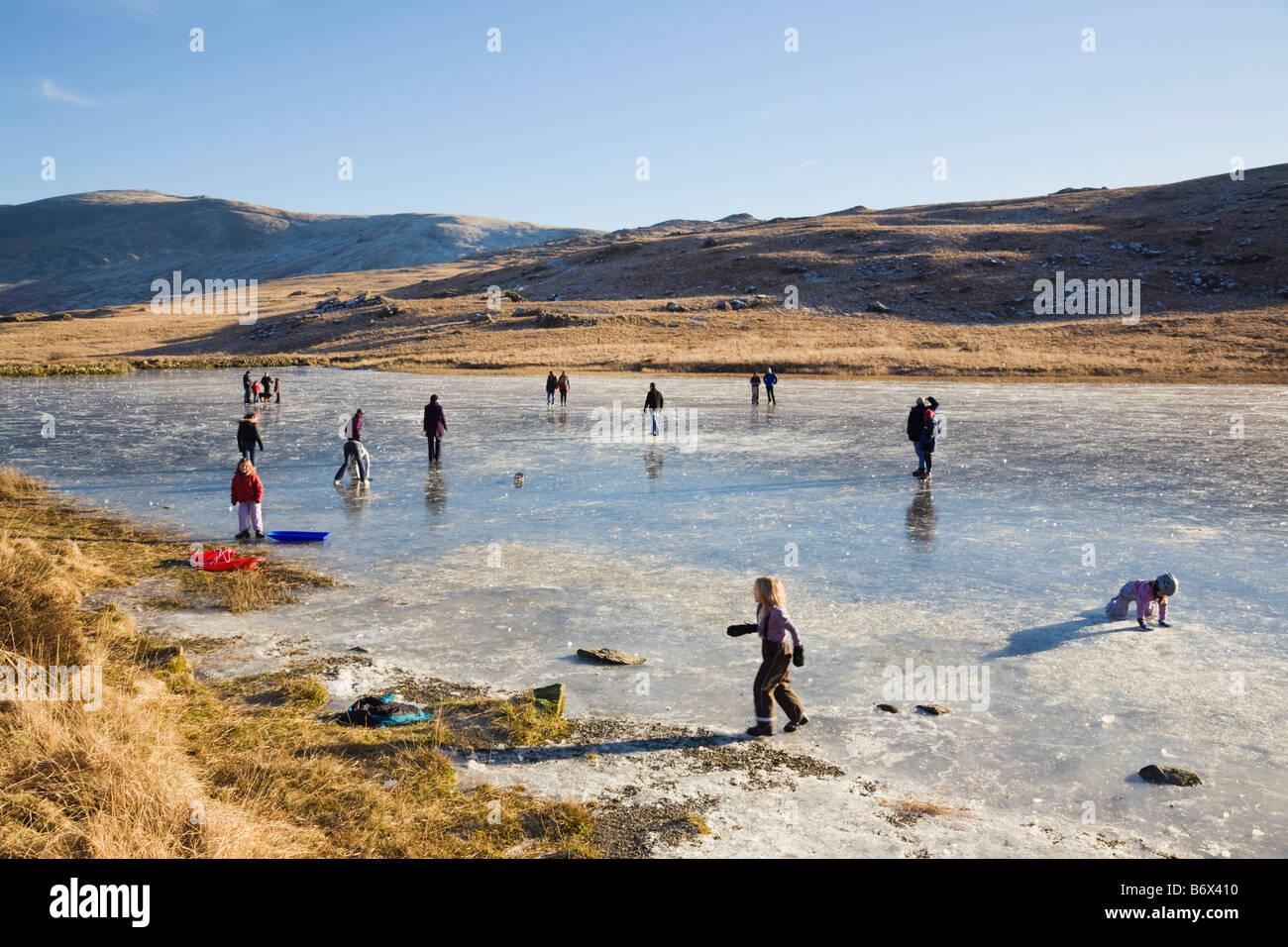 Lockwoods Lake Pen-y-Gwryd Snowdonia National Park North Wales UK People playing on frozen lake ice in winter Stock Photo