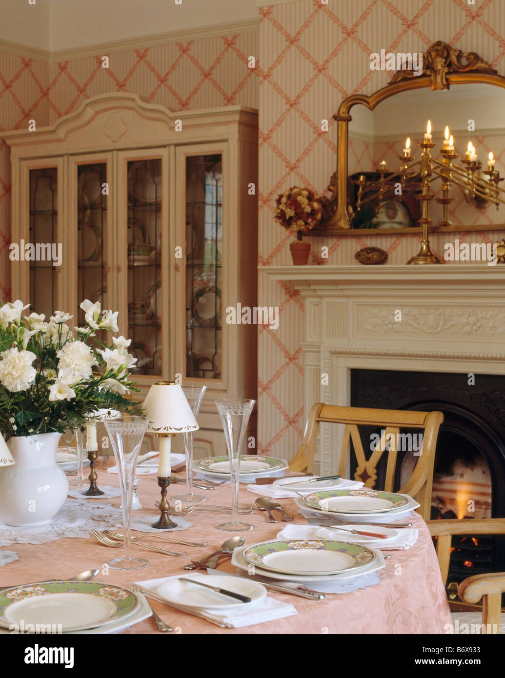 Gilt mirror above candelabra on mantelpiece in dining room with pink