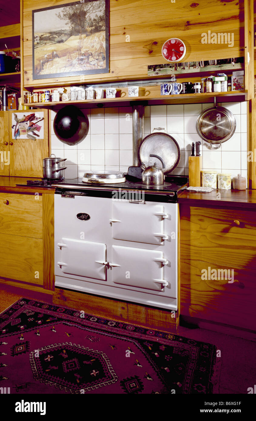 Picture on wooden cupboard above white Aga oven in traditional kitchen