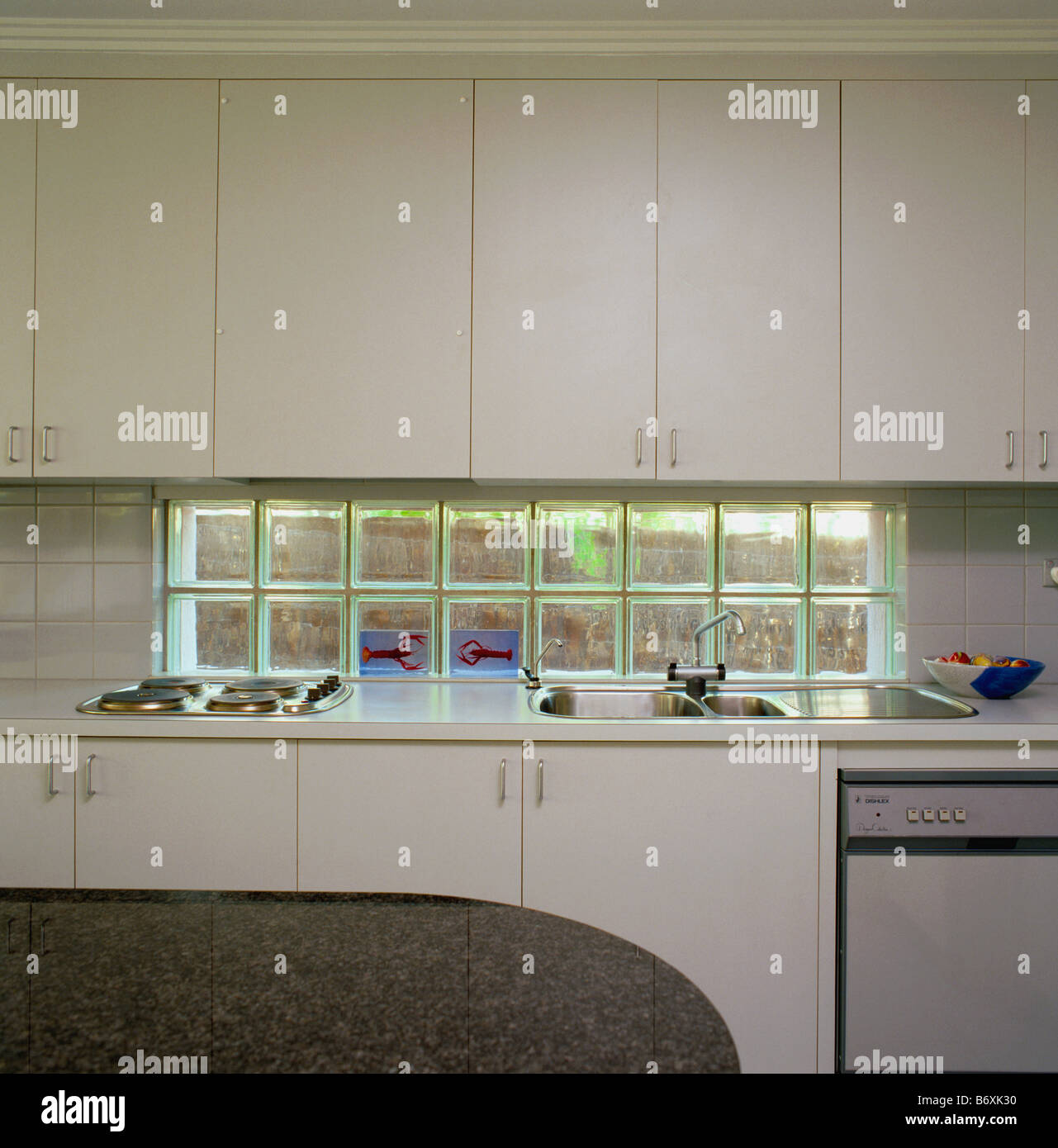 Narrow Glass Brick Window Above Worktop With Sink And Built In Hob In Modern White Kitchen With White Wall Cupboards Stock Photo Alamy