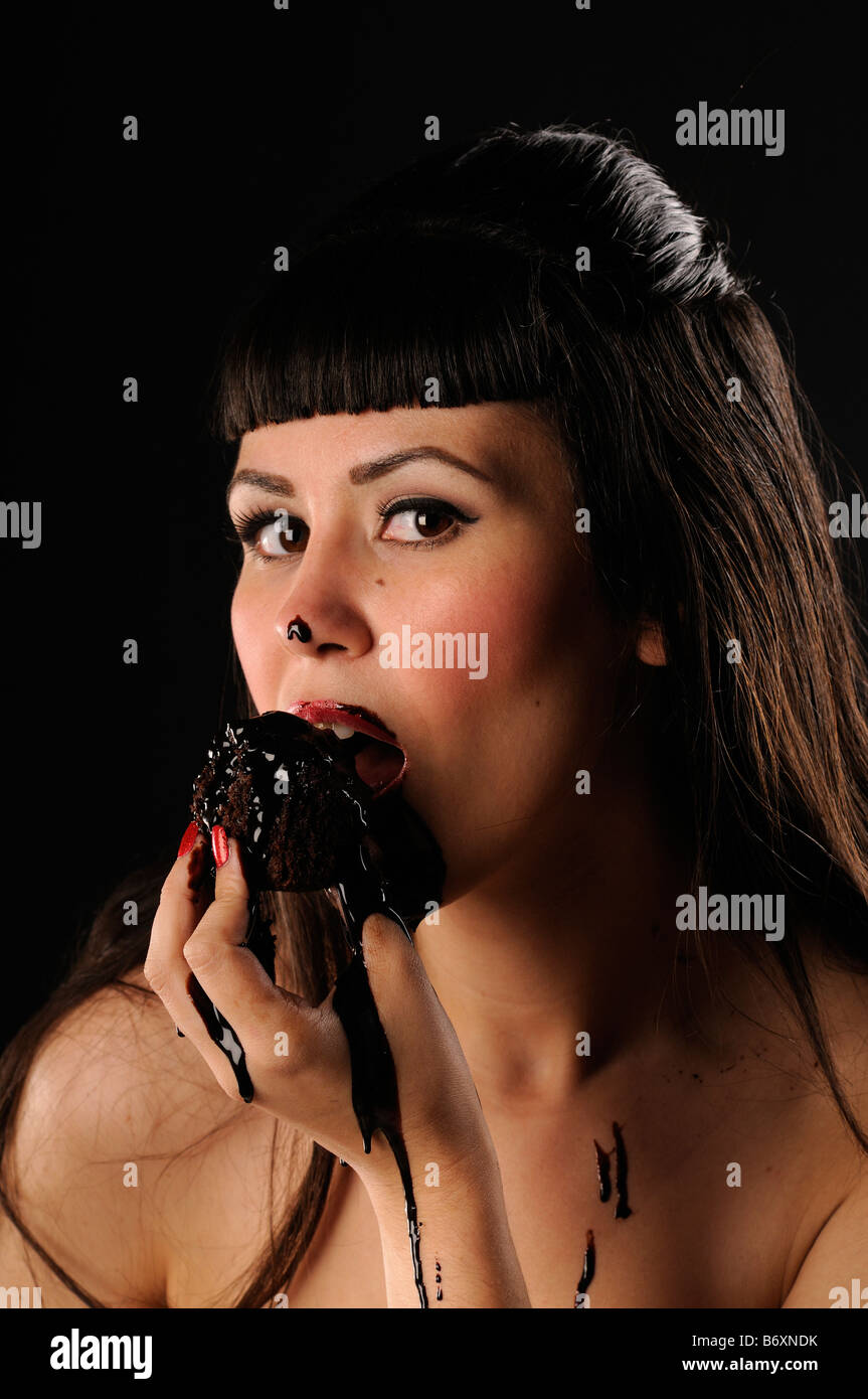 Pretty girl eating a muffin with dripping liquid chocolate Stock Photo