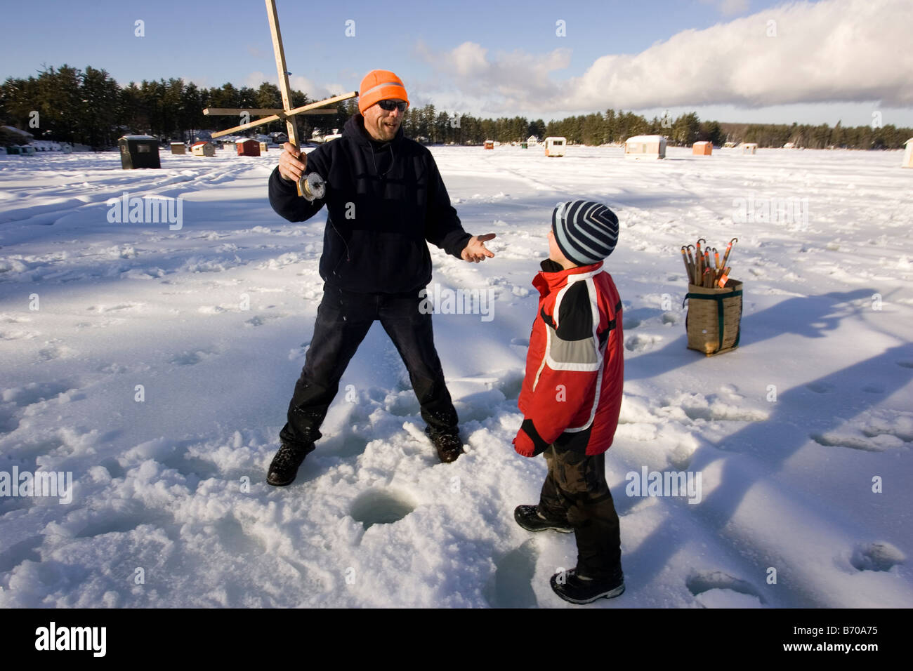 A man teaches a boy how to ice fish on Maine Lake in North Waterboro