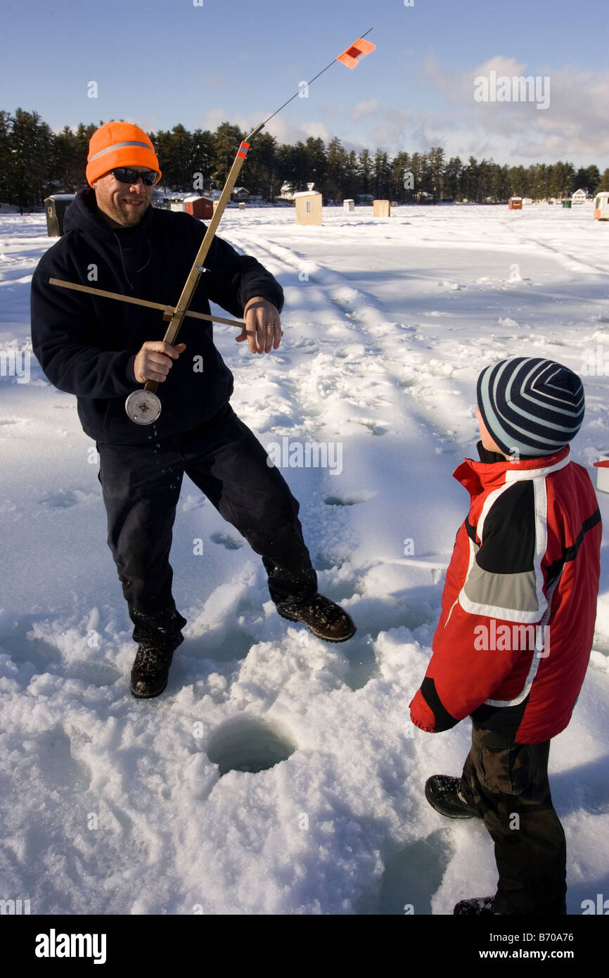 A man teaches a boy how to ice fish on Maine Lake in North Waterboro