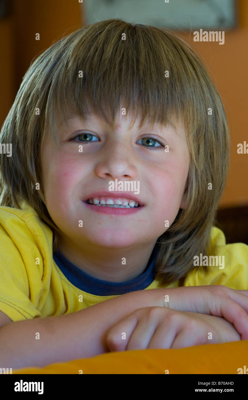 Smiling bright eyed 5 year old boy with long hair Stock Photo