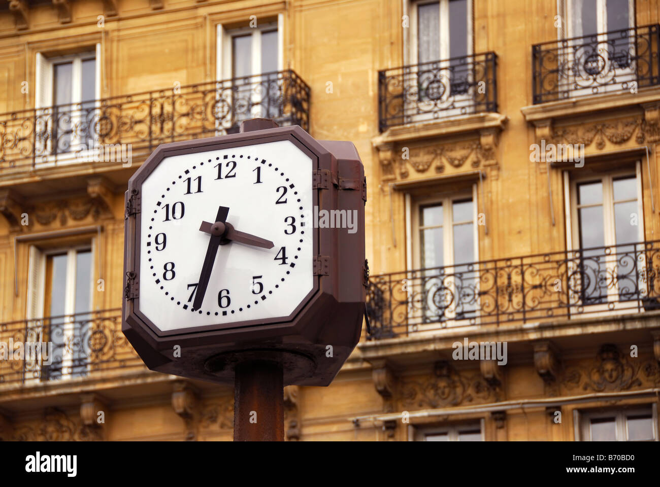 Public clock in Paris on background of old apartment building Stock Photo