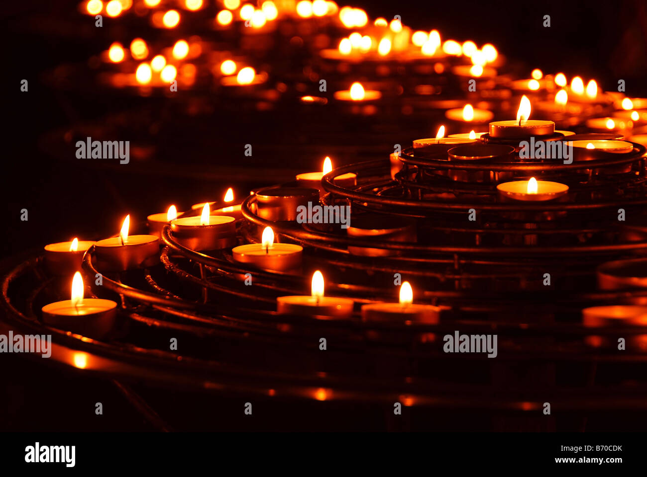 Rows of burning candles in a cathedral Stock Photo