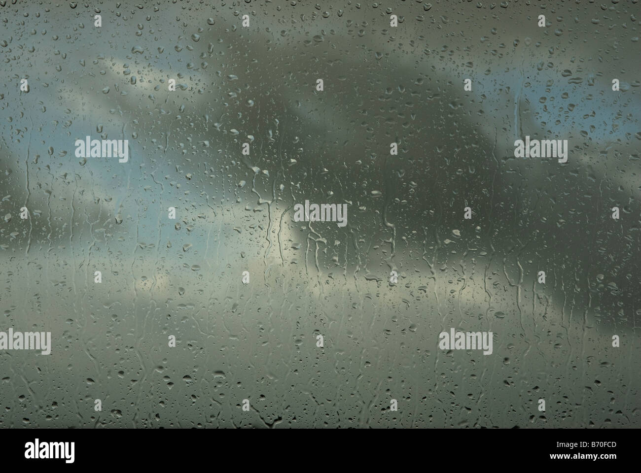 Water droplets on a window with storm clouds behind Stock Photo