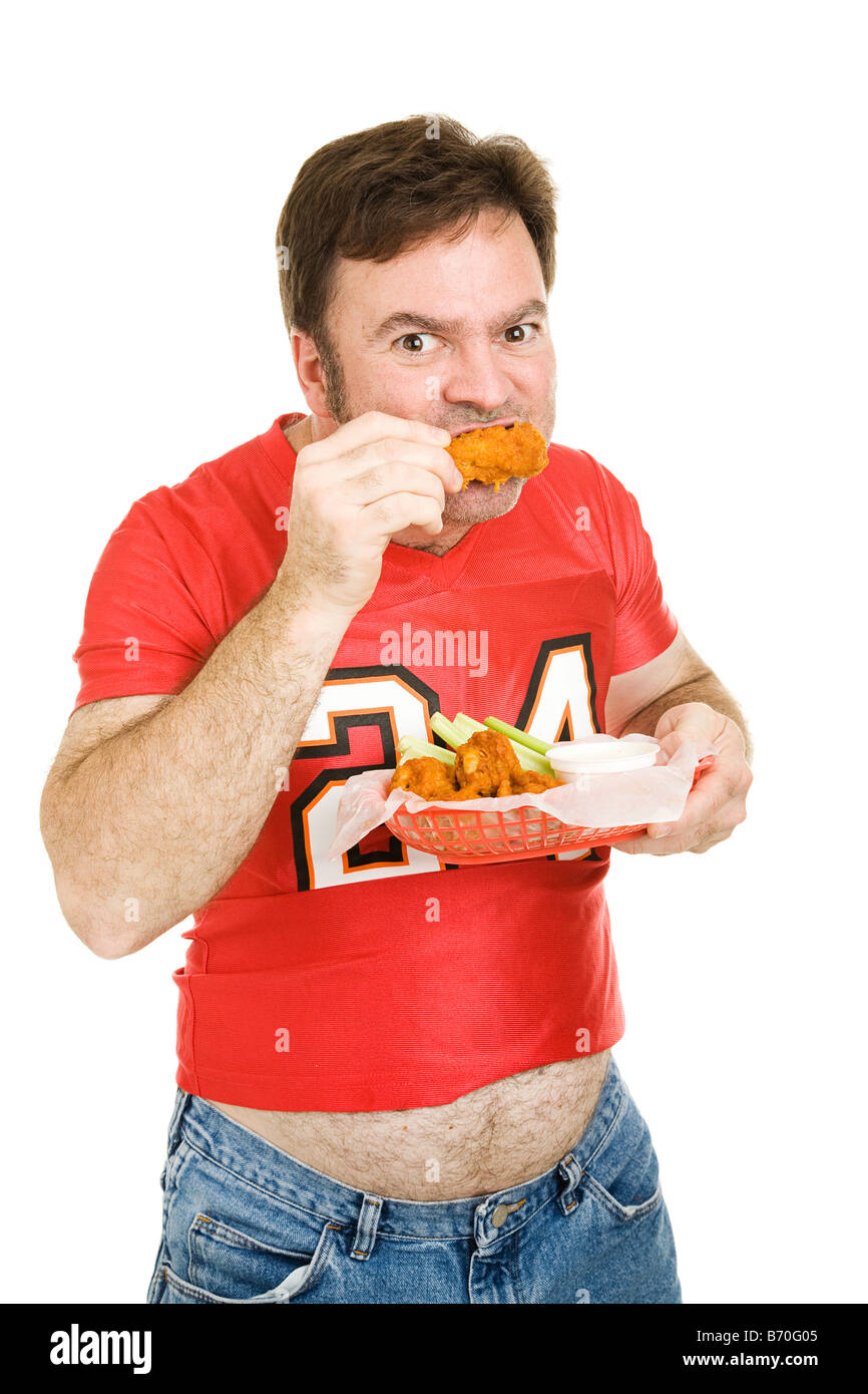 Overweight middle aged man in tight football jersey chowing down on fried chicken wings Isolated on white Stock Photo