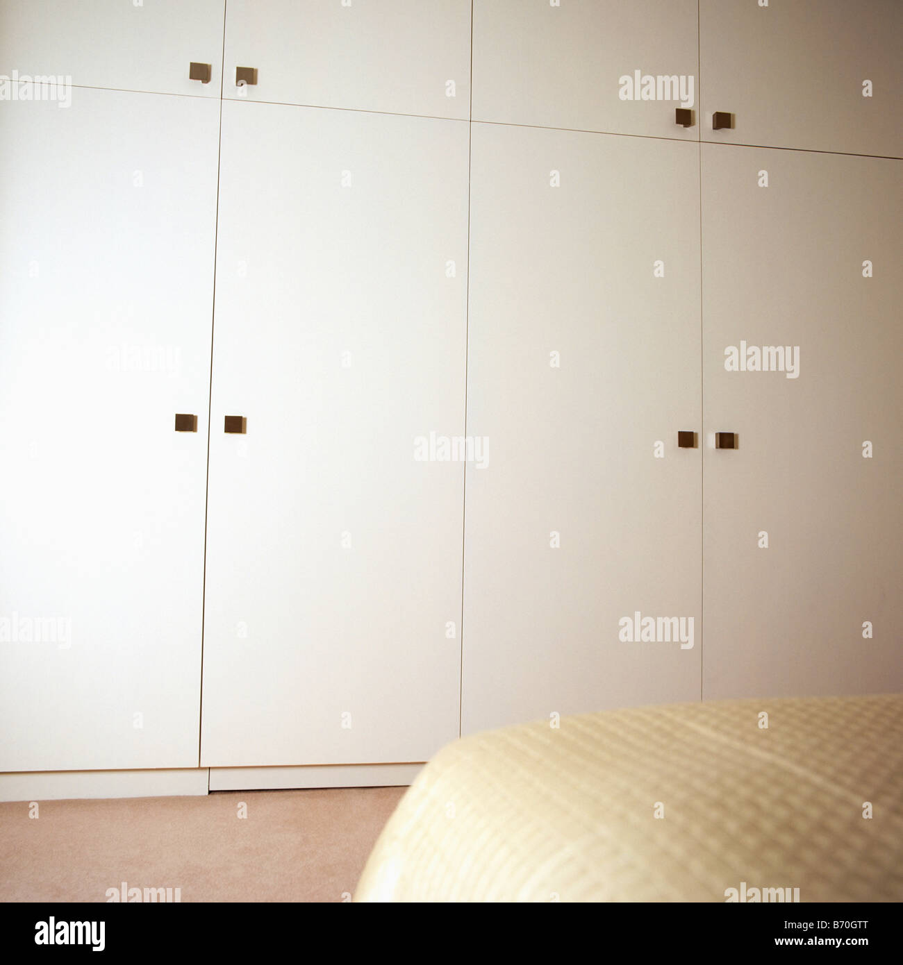 Cream fitted storage cupboards in economystyle bedroom Stock Photo Alamy