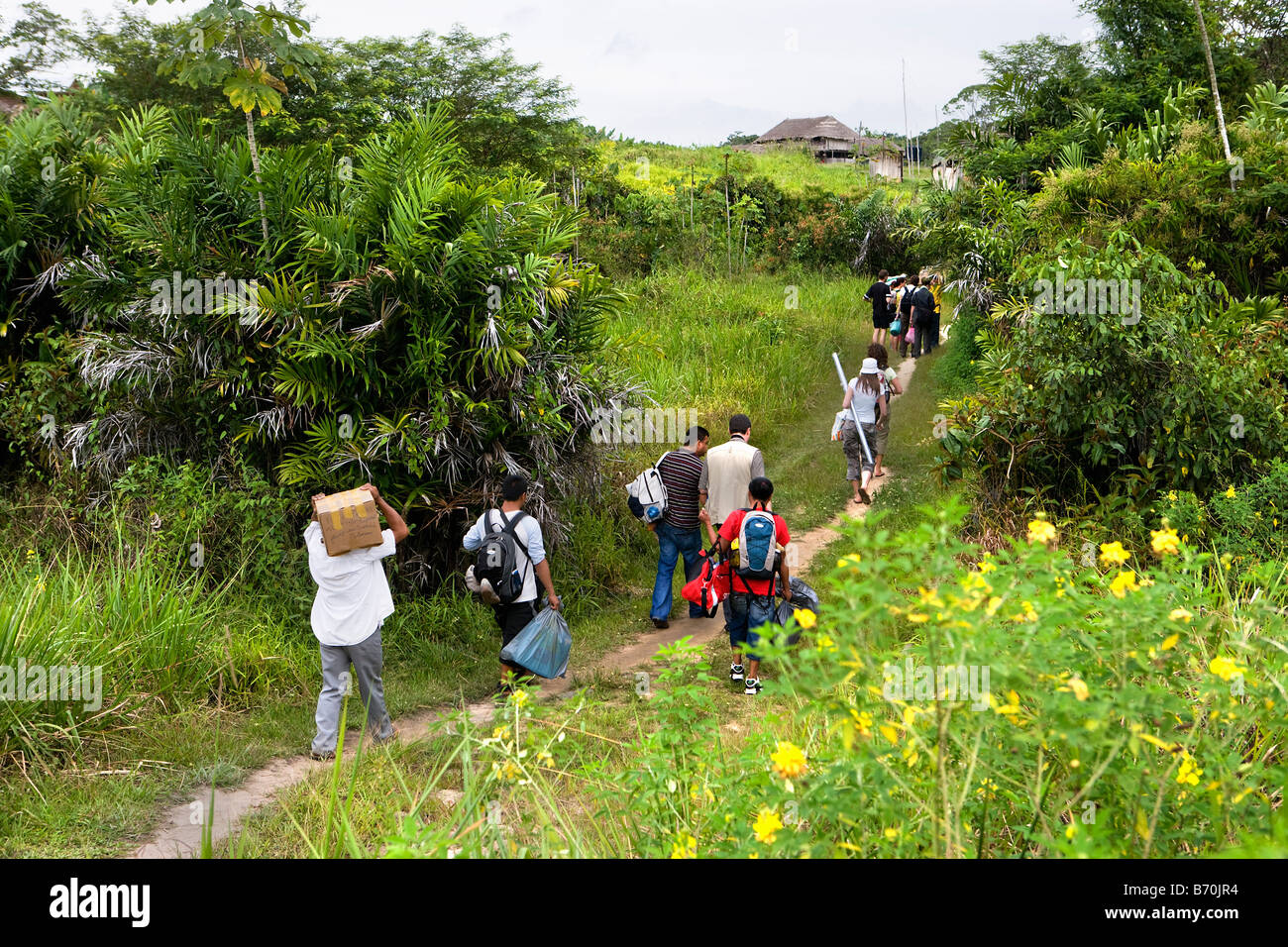 Suriname, Kwamalasamutu, home of indigenous Indians. Tourists arriving. Walking to village with luggage from airport. Stock Photo