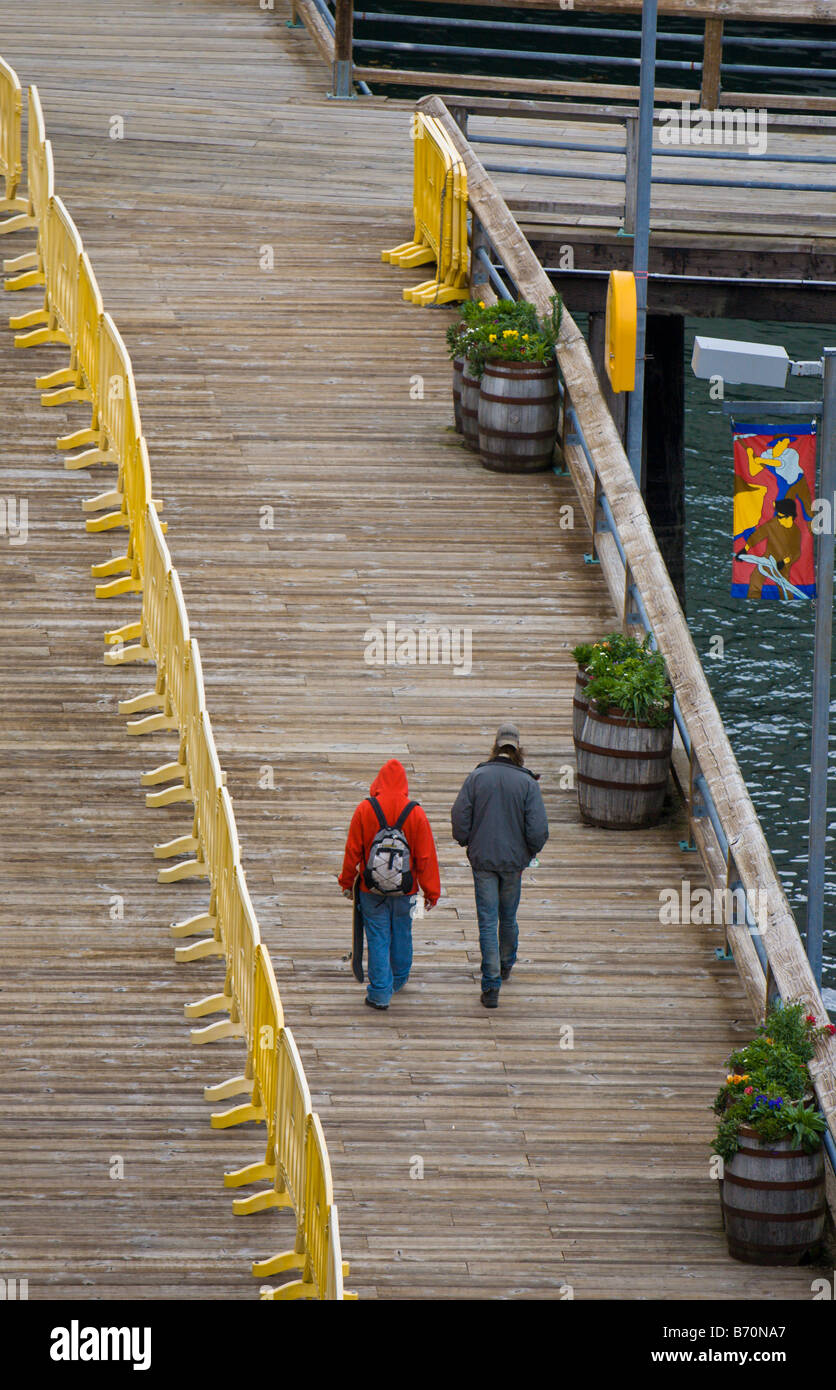 Cruise ship passengers walk away from ship on wooden boardwalk at the Juneau, Alaska port Stock Photo