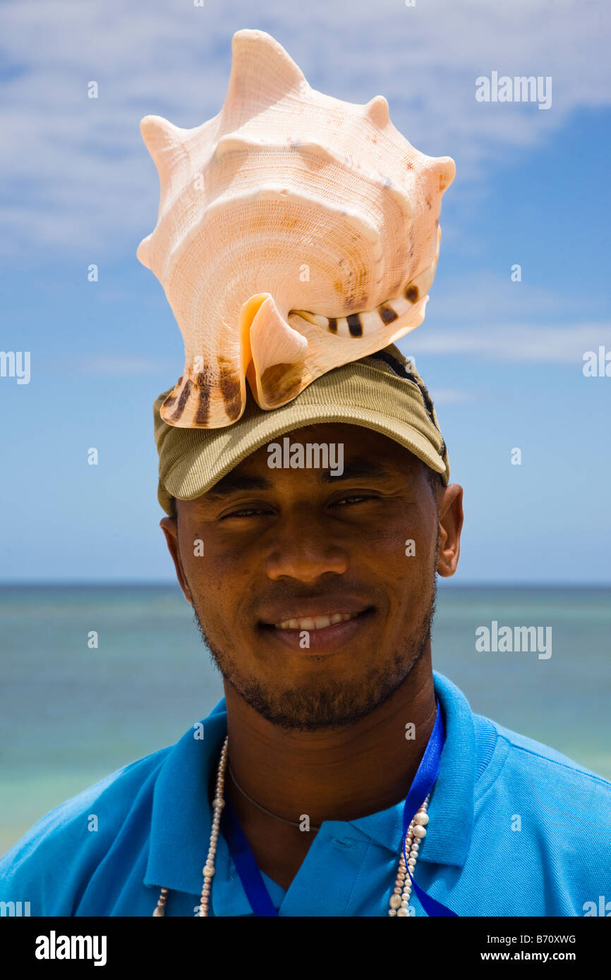 Man on the beach in Mauritius selling large conch shells taken by diving from the Indian Ocean Stock Photo