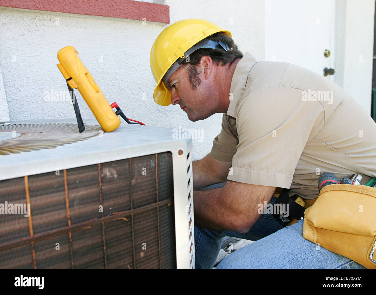 An air conditioning repairman working on a compressor unit Stock Photo